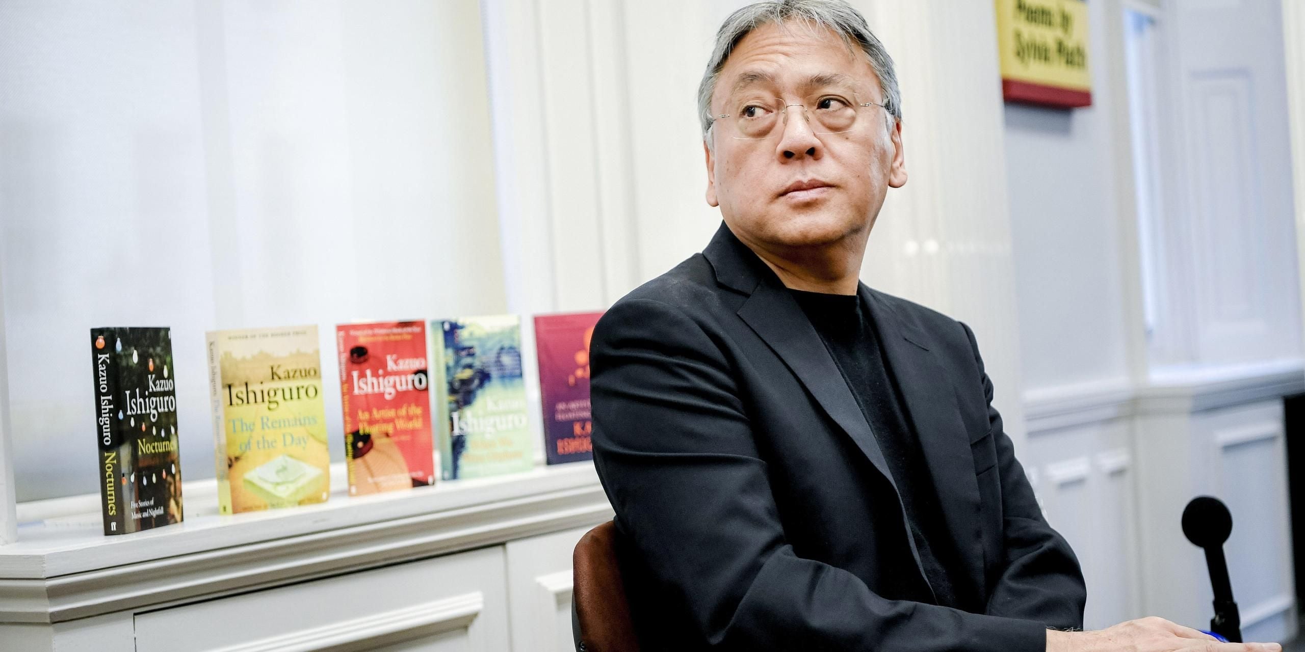 Author Kazuo Ishiguro sitting in front of his books.