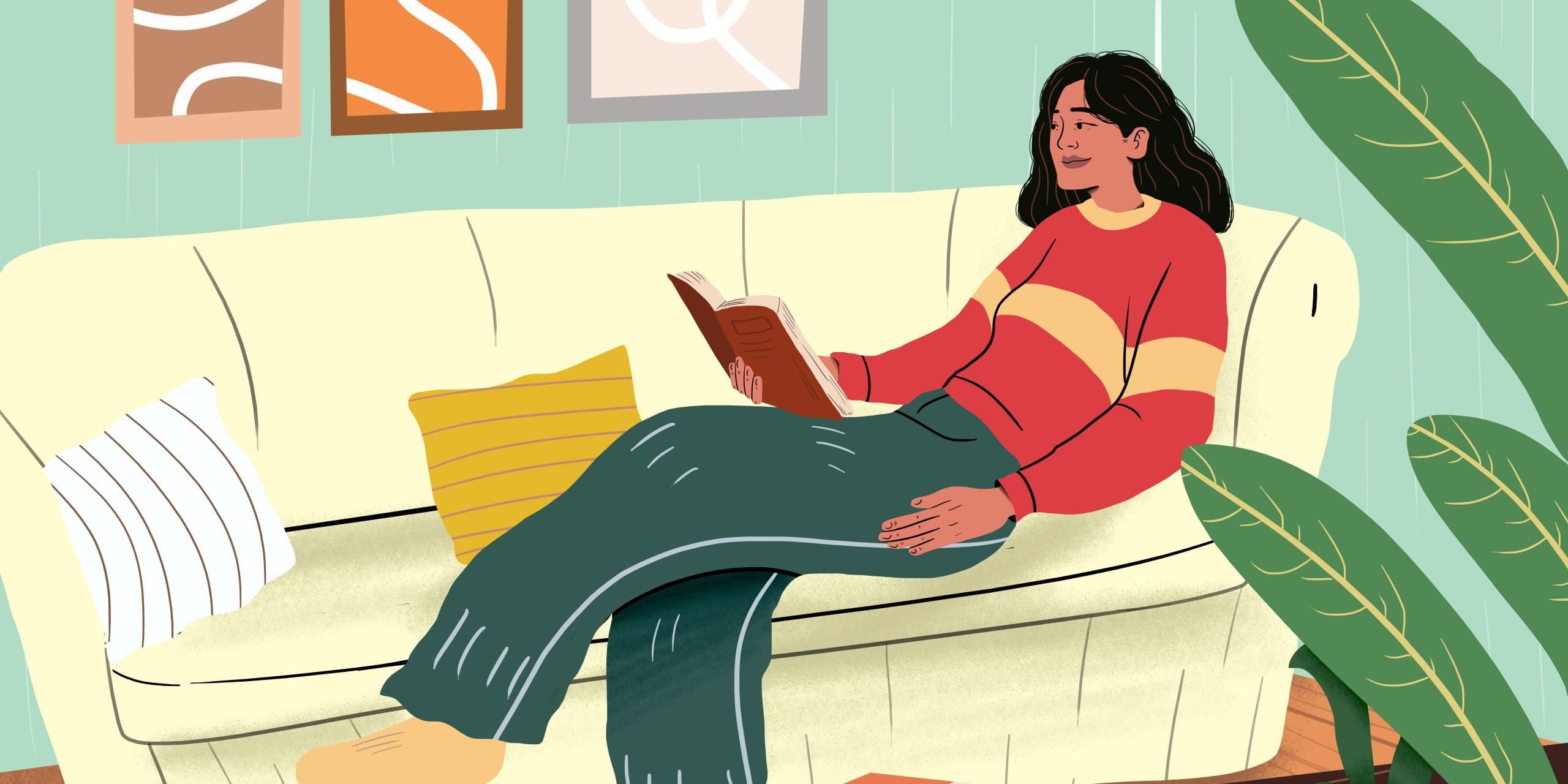 Woman reading book and lying on sofa at home.