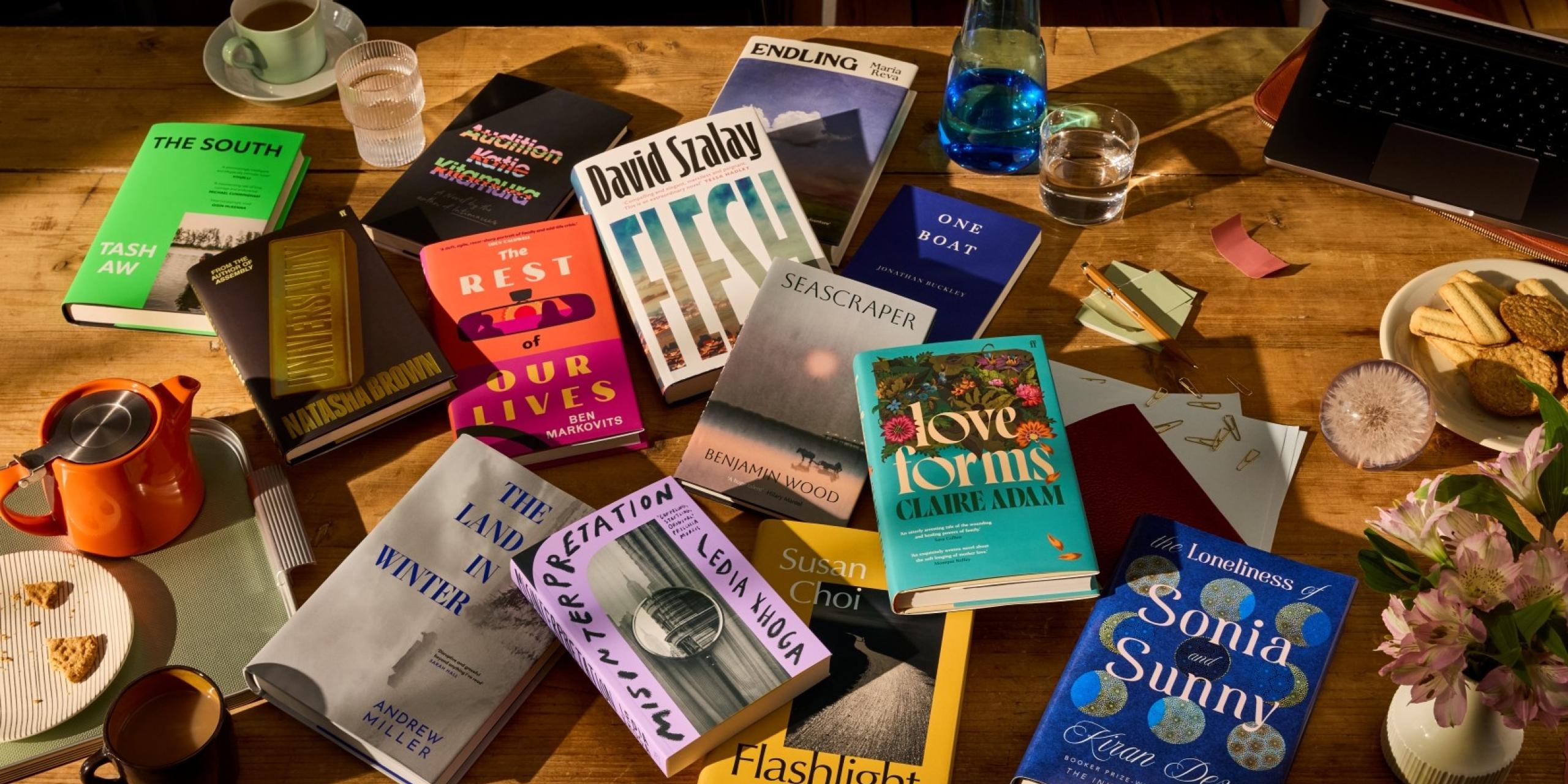 The Booker Prize 2025 longlist of 13 books, scattered across a table