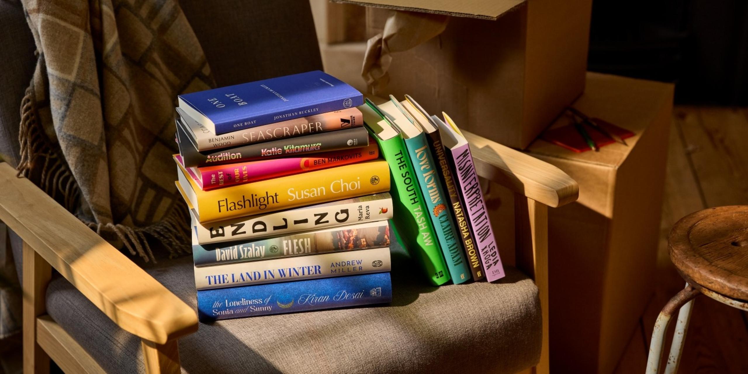 The Booker Prize 2025 longlist of 13 books, displayed on an armchair
