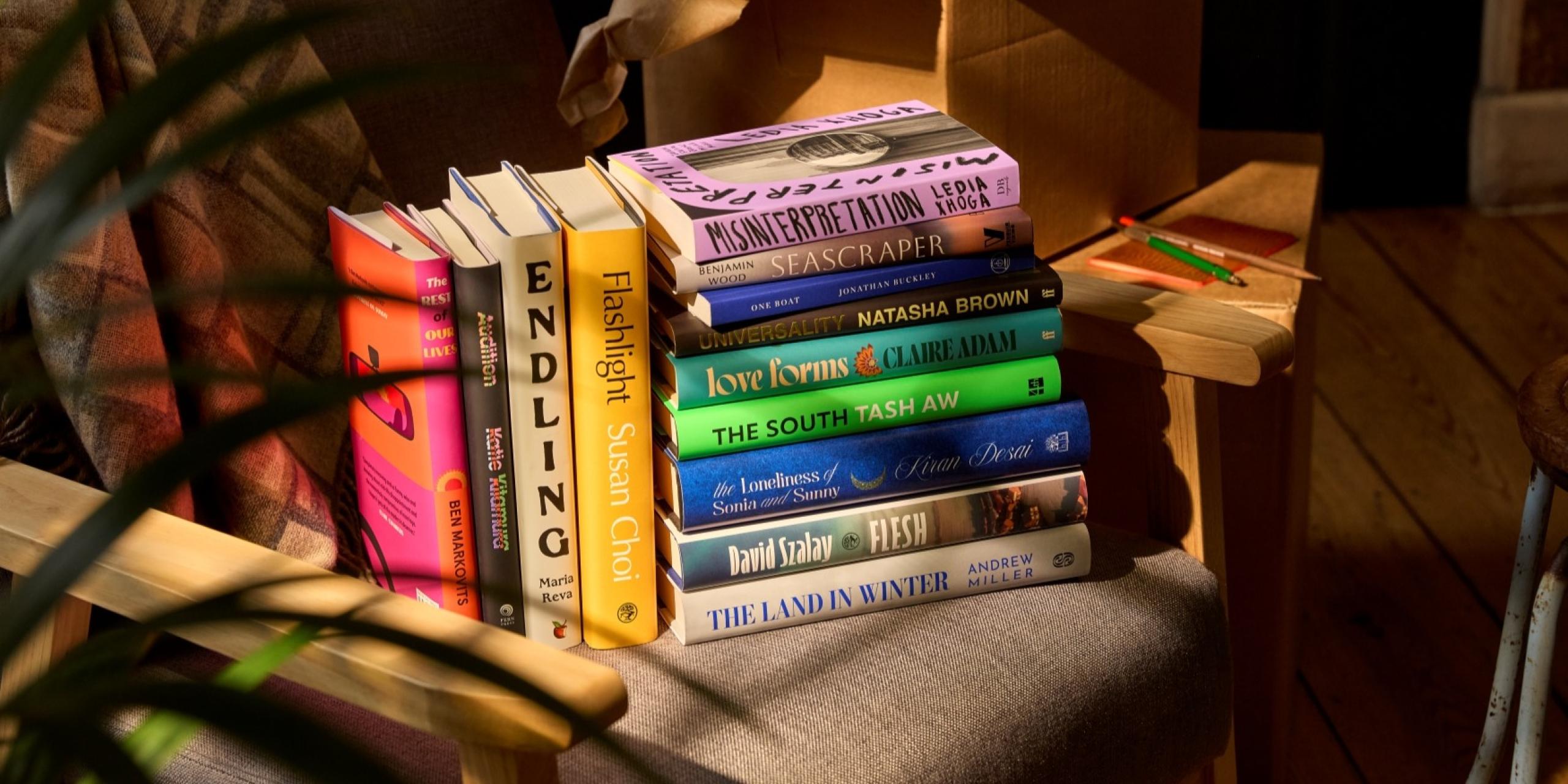 The Booker Prize 2025 longlist of 13 books, displayed on an armchair