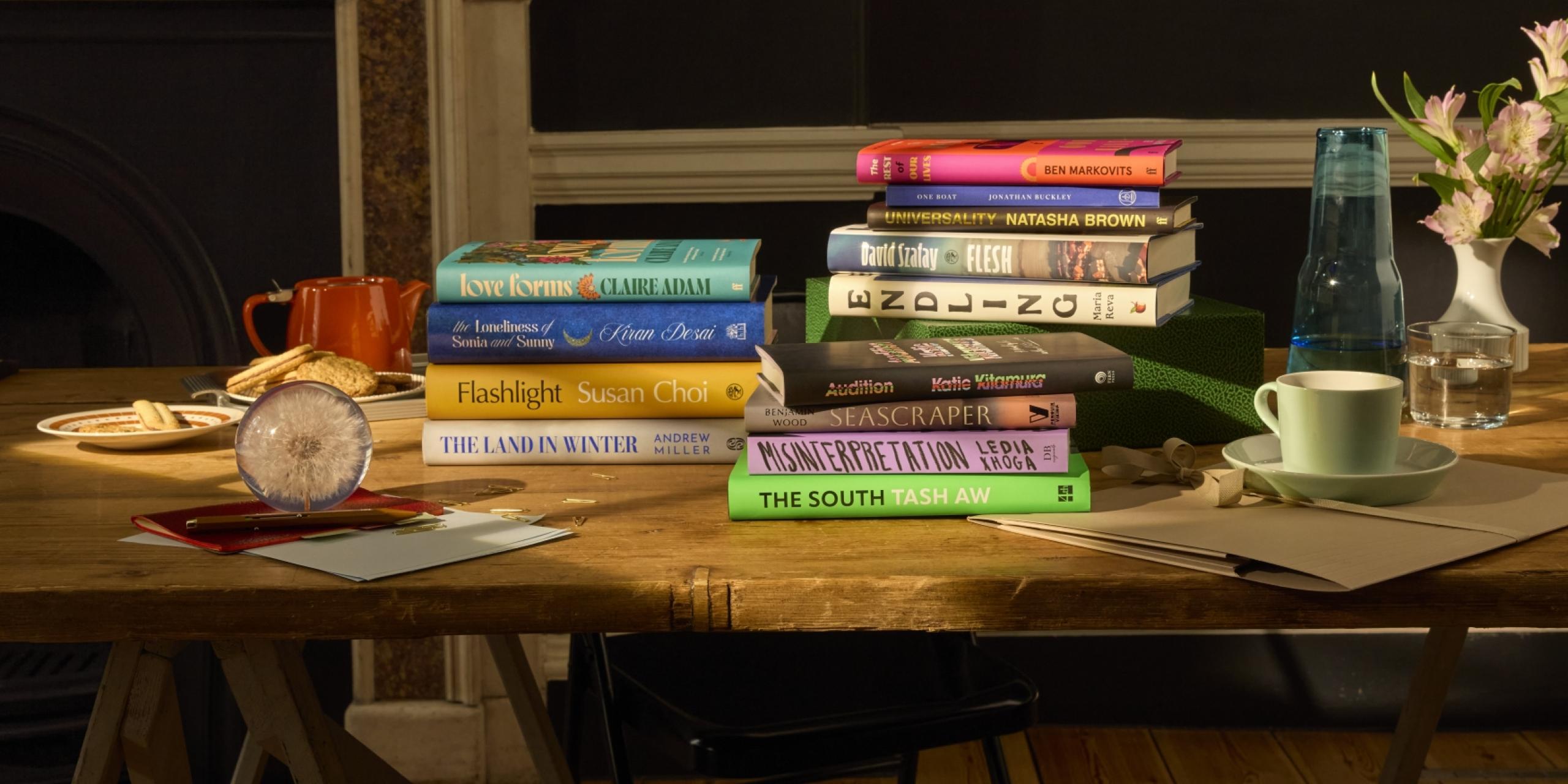 The Booker Prize 2025 longlist of 13 books, displayed artfully on a table