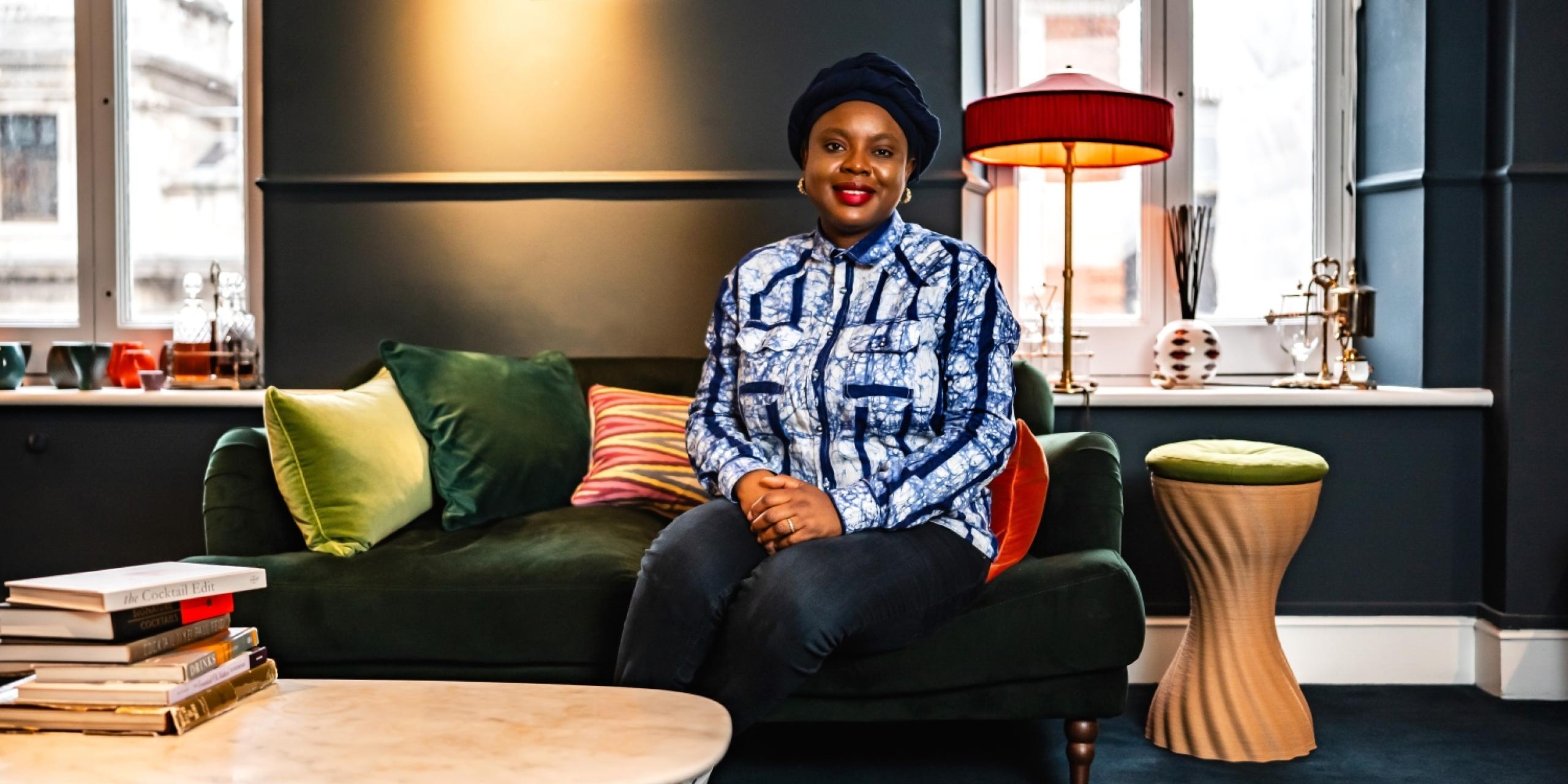 Ayòbámi Adébáyò is sitting on a green sofa
