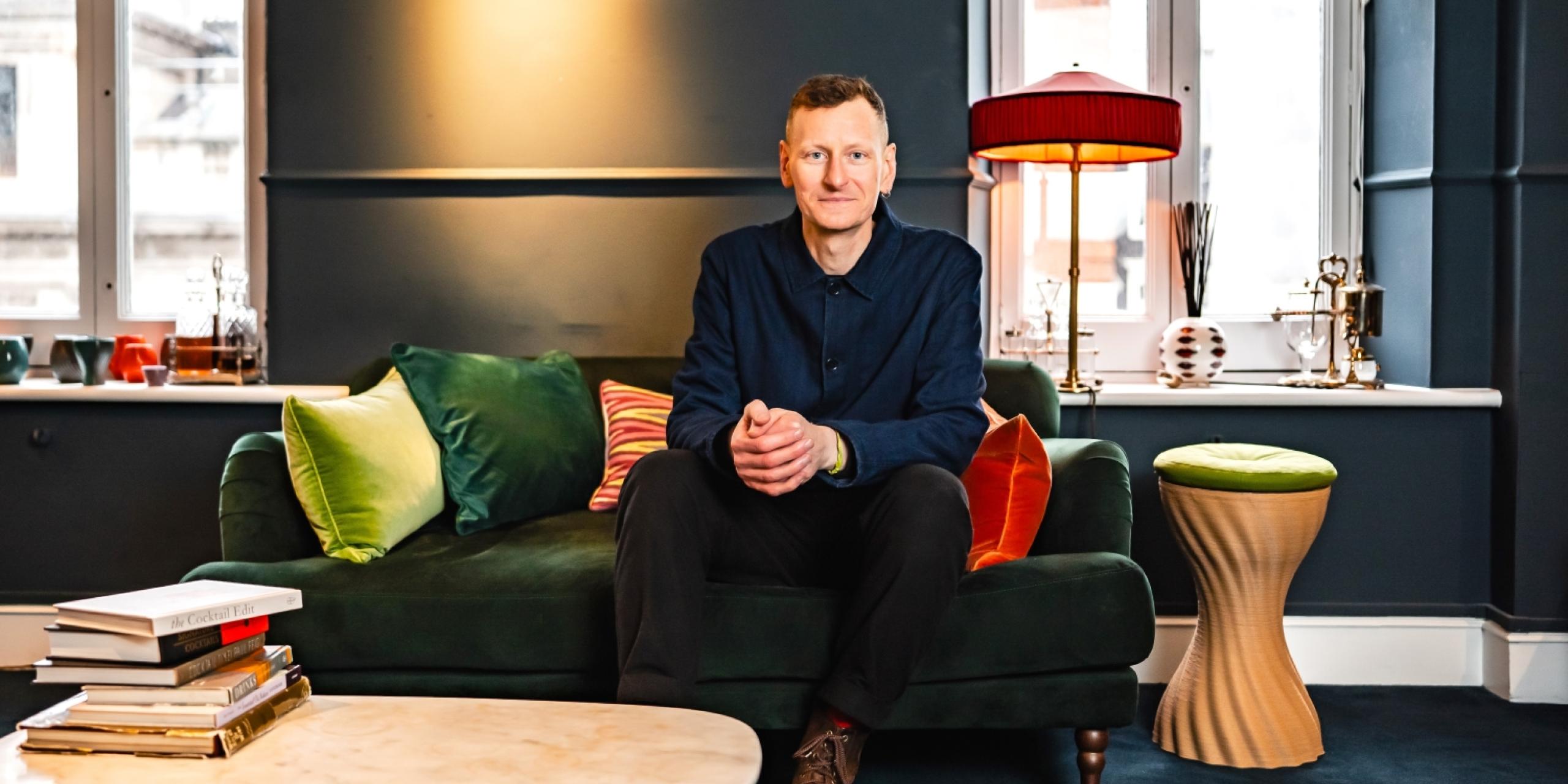 Chris Power sitting on a green velvet sofa