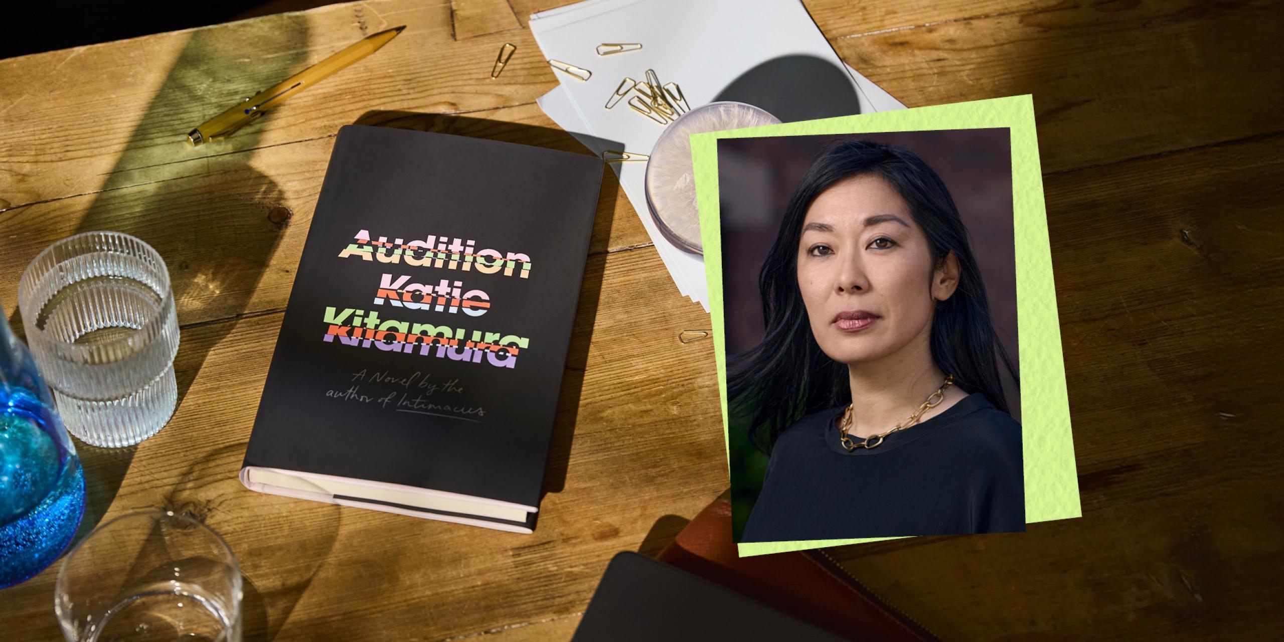 The book Audition is lying on a desk next to a glass of water and an image of Katie Kitamura