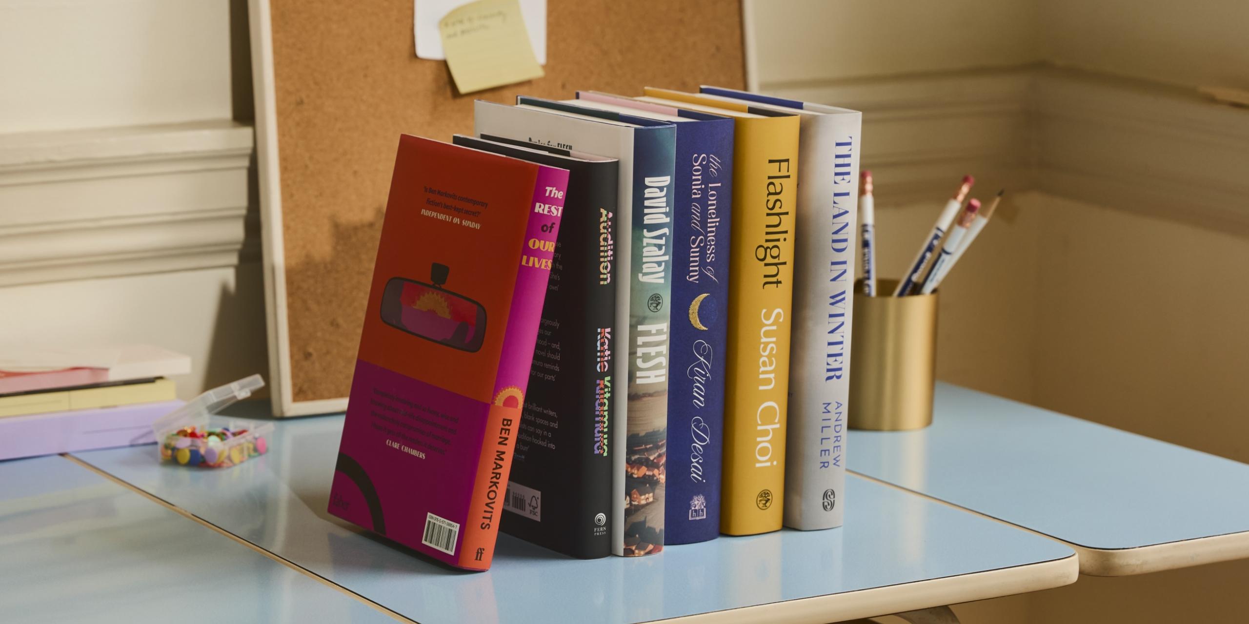 The Booker Prize 2025 shortlist of six books, displayed artfully on a desk