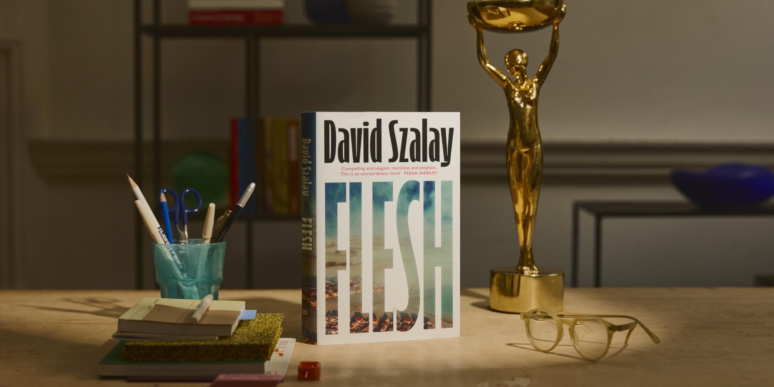 A copy of the novel, Flesh by David Szalay, pictured alongside the Booker Prize trophy