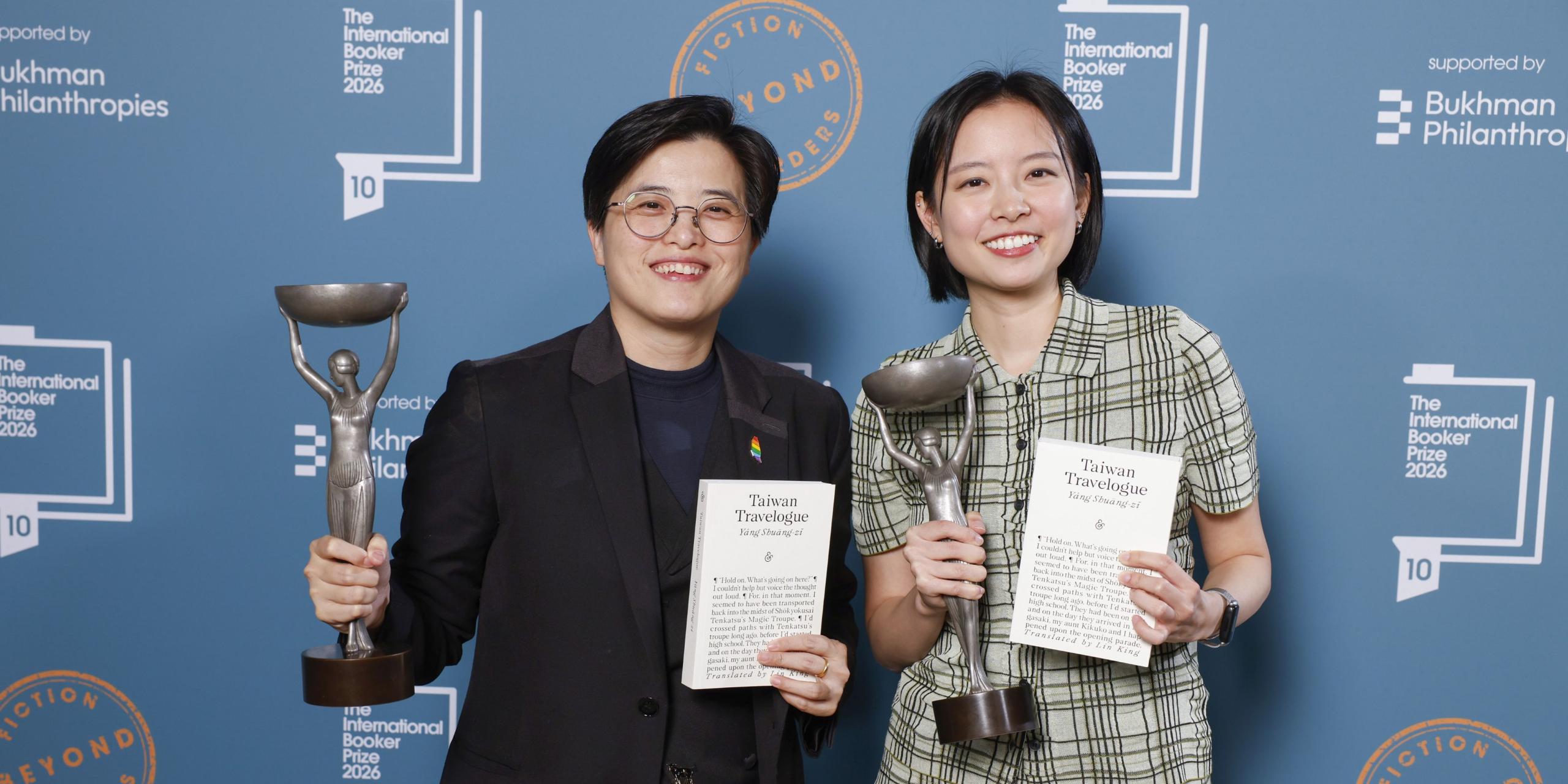 Author Yáng Shuāng-zǐ and translator Lin King each holding a copy of Taiwan Travelogue and their International Booker Prize trophies