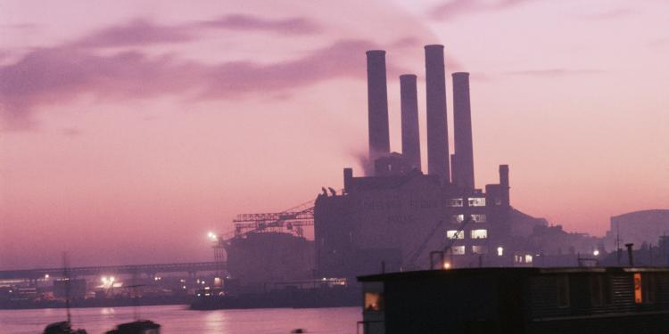 A pink-tinged image of Chelsea Flour Mills in silhouette, with the River Thames in the foreground.