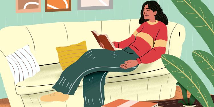 Woman reading book and lying on sofa at home.